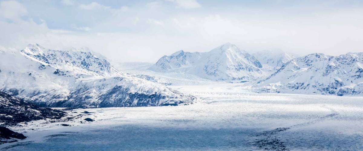 Eagle Peak, Alaska - April 10, 2017: An extreme wide aerial view of Eagle Peak mountains in Alaska with cloudy shades crossing the frozen lake