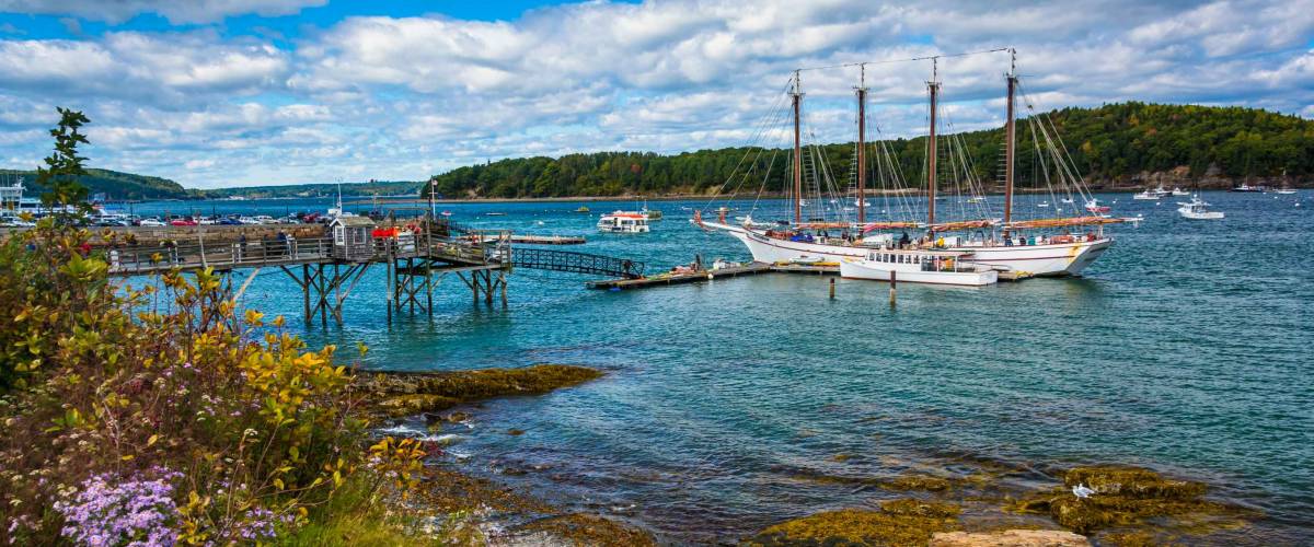 Rocky coast and view of boats in the harbor at Bar Harbor, Maine.